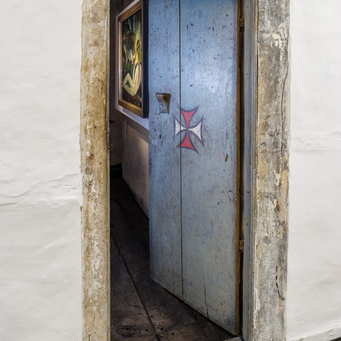 Nahaufnahme einer alten geöffneten Tür. Auf der Tür ist ein weiß-rotes Kreuz. (vergrößerte Bildansicht wird geöffnet)
