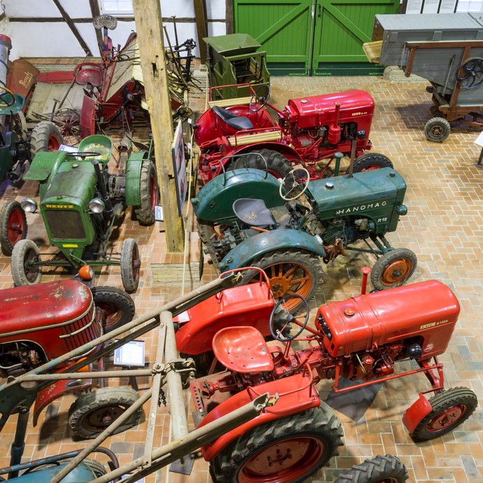 In der Ausstellungshalle stehen rote und grüne Traktoren. (vergrößerte Bildansicht wird geöffnet)