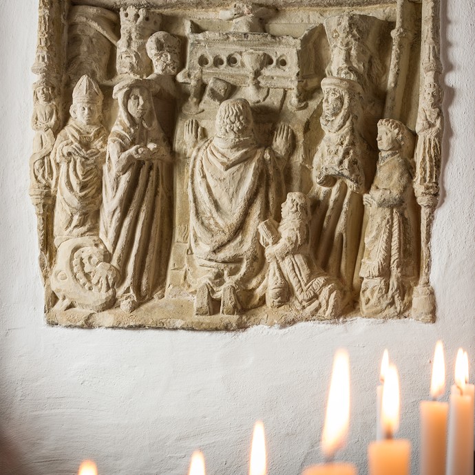 Hinter brennenden Kerzen befindet sich das Sandstein-Relief aus dem 15. Jh., welches Papst Gregor I. zeigt. (vergrößerte Bildansicht wird geöffnet)