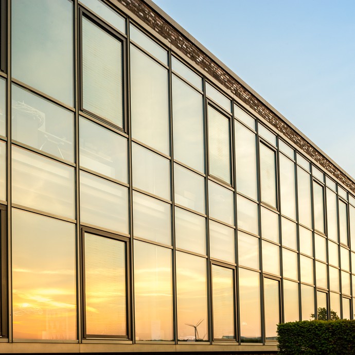 Die Abendsonne spiegelt sich in der gläsernen Bürofassade der Firma Eimermacher. (vergrößerte Bildansicht wird geöffnet)