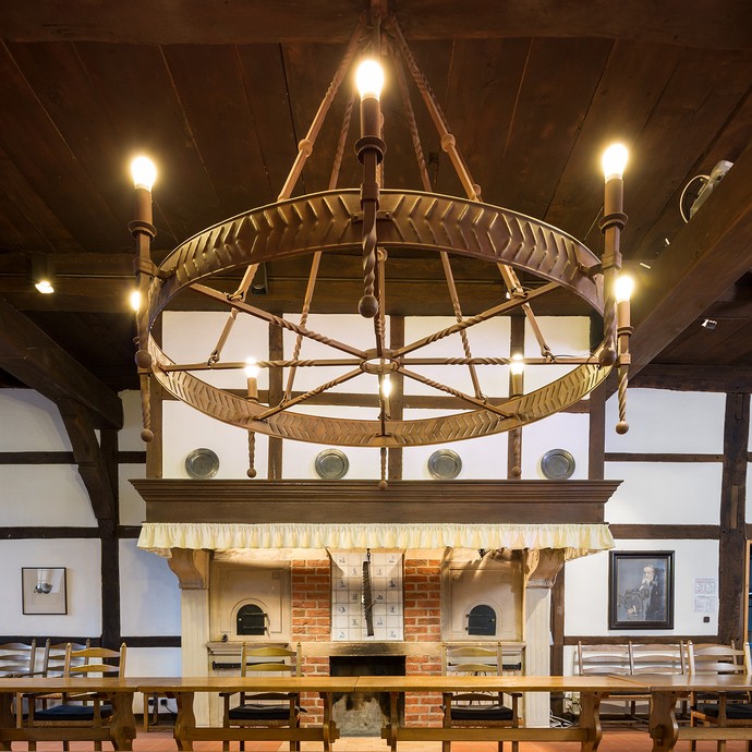 Blick in den Ratssaal mit vielen Tischen und Stühlen. Von der Decke hängt ein riesiger Leuchter herunter. (vergrößerte Bildansicht wird geöffnet)
