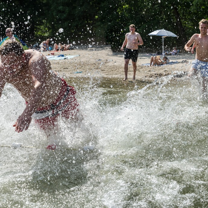 Eine Gruppe von Jungen geht ins Wasser schwimmen. Beim Hereinlaufen ins Wasser spritzt das Wasser. (vergrößerte Bildansicht wird geöffnet)