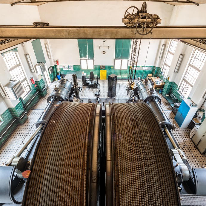 Innenaufnahme in der Zeche. Blick von oben in die Maschinenhalle. Im Vordergrund sind die hellbraunen Seile der Seilbahn aufgerollt. (vergrößerte Bildansicht wird geöffnet)