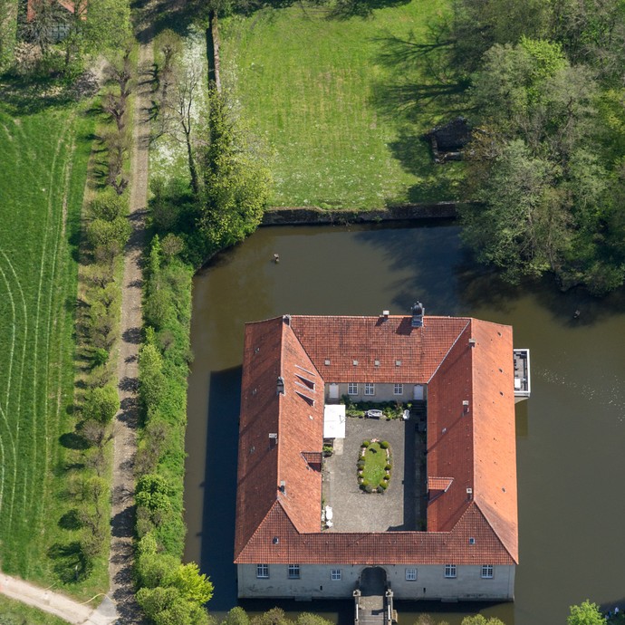 Das Wasserschloss Haus Marck aus der Luft fotografiert. Ein Wassergraben, Felder und Wege umrahmen das Gebäude. (vergrößerte Bildansicht wird geöffnet)