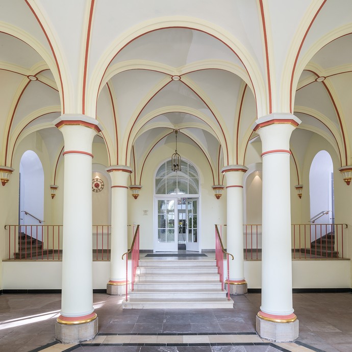 Blick in die helle Eingangshalle. Bögen und Säulen lassen die Halle sehr imposant erscheinen. (vergrößerte Bildansicht wird geöffnet)
