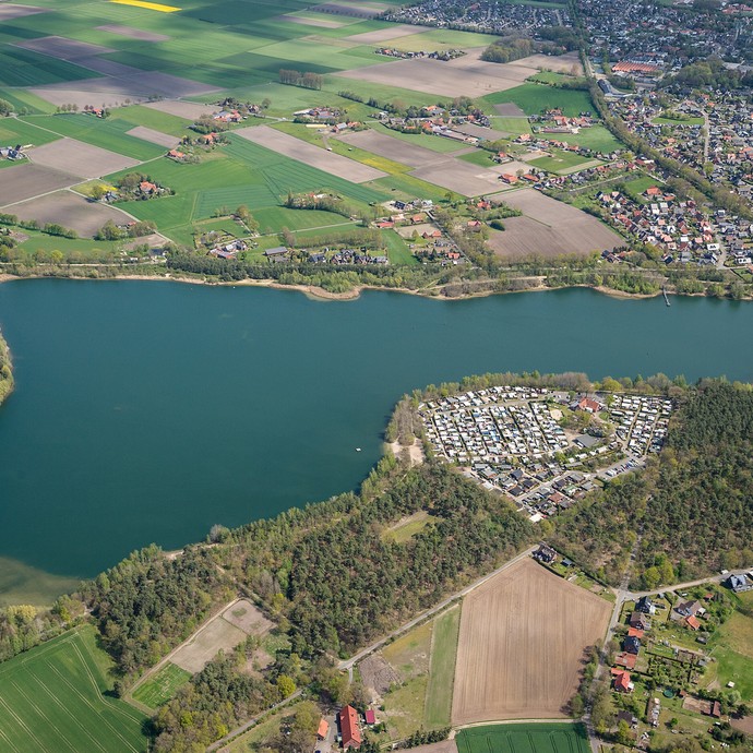 Luftaufnahme des Offlumer Sees. Er ist umgeben von Feldern in landwirtschaftlicher Nutzung und Wohnhäusern der Gemeinde Neuenkirchen. (vergrößerte Bildansicht wird geöffnet)