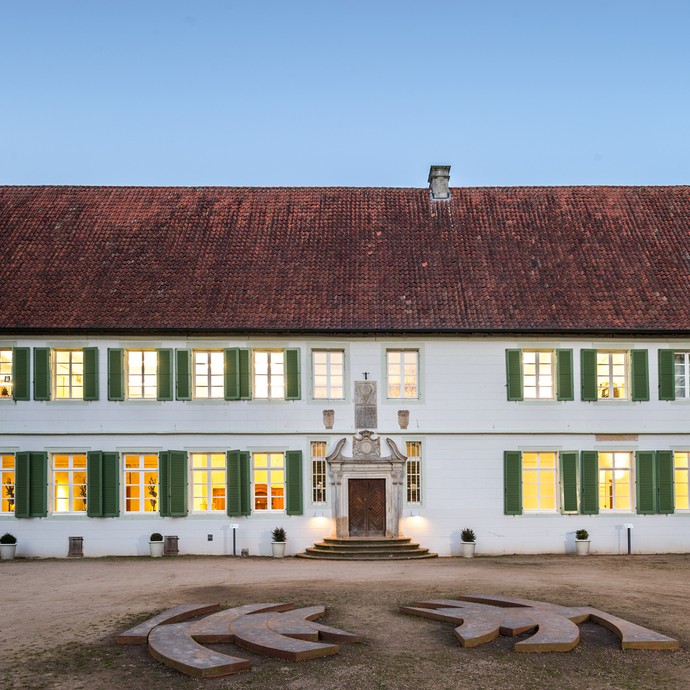 Blick auf den Ostflügel des Gebäudes. Das Gebäude ist weiß und hat viele Fenster mit grünen Fensterläden. (vergrößerte Bildansicht wird geöffnet)